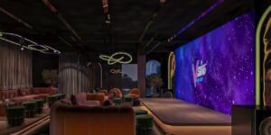 Modern lounge with stage, large LED screen, and plush seating.