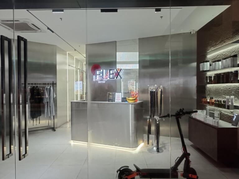Sleek modern store entrance with FLEX sign, products, clothing, scooter.