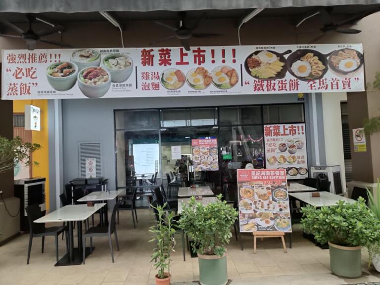 Asian restaurant storefront with outdoor seating and food banners.