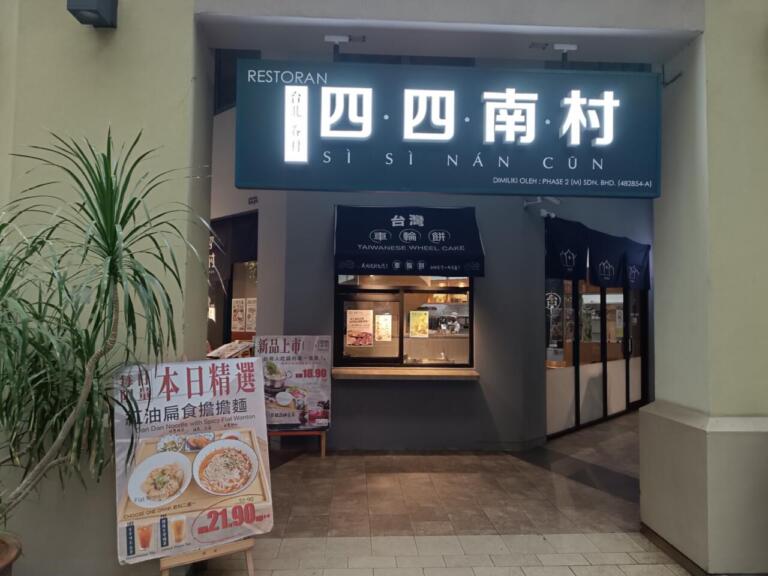 Taiwanese restaurant storefront with illuminated sign and menu standee.