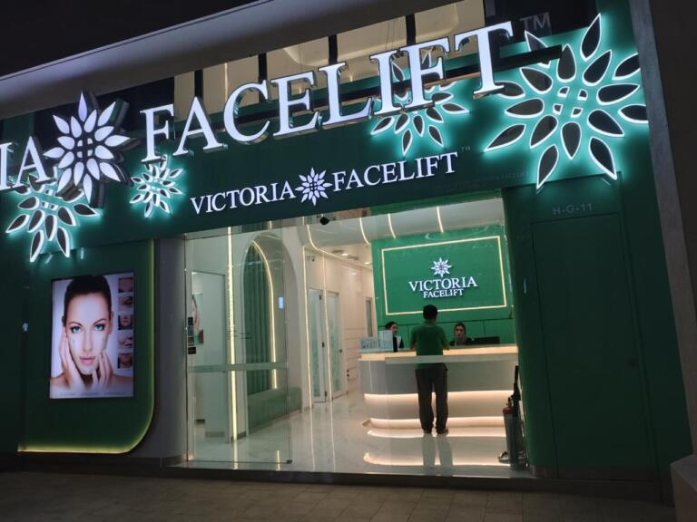 Illuminated Victoria Facelift clinic exterior with woman's face advertisement.